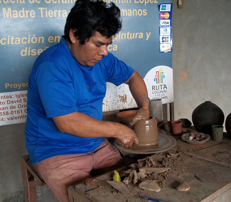 Artisan craftsman shapes a clay pot on a traditional pottery wheel in an art workshop.