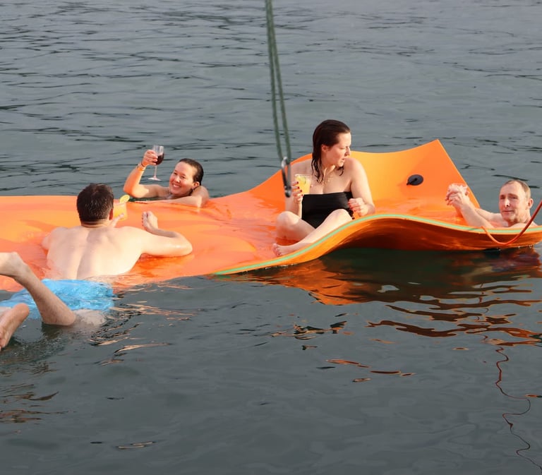 Guests relaxing on floating mat with cocktails during luxury catamaran experience in Papagayo