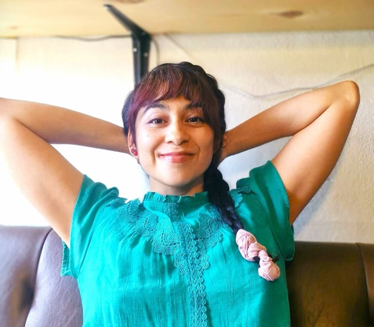 Mujer sentada en un sillon, tomandose un momento para relajarse con las manos en su nuca. 