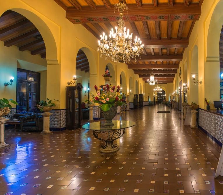 Elegant historic hotel lobby featuring Spanish colonial architecture, tiled floors, and crystal chandeliers.