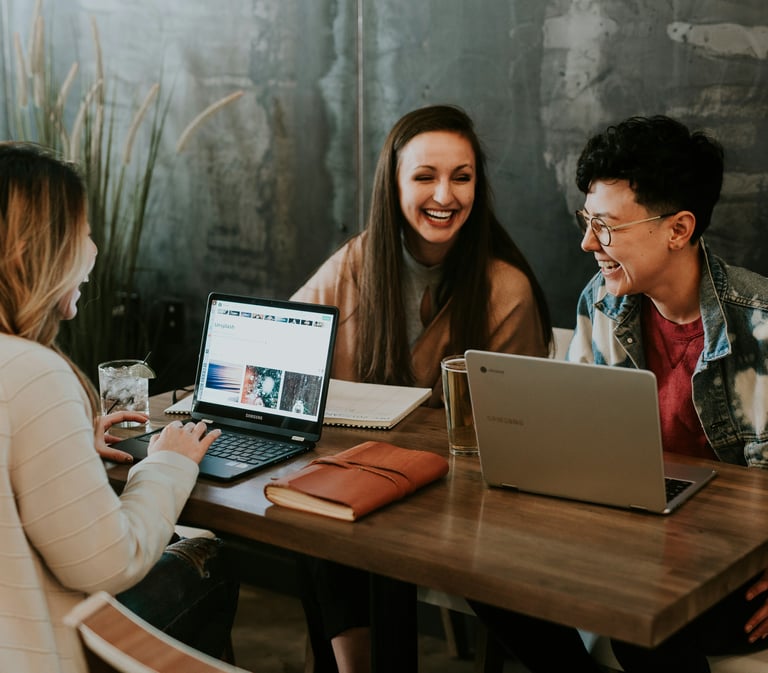 a group of people sitting at a table with laptops