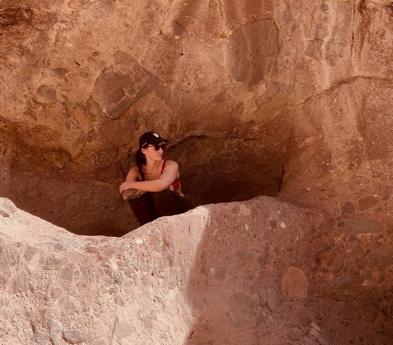 A woman hiker resting in a rocky desert alcove during a scenic canyon exploration in Arizona.