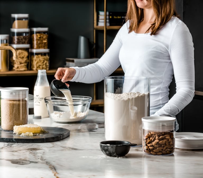 Food product photography - a woman in a white shirt pouring milk in a bowl of flour