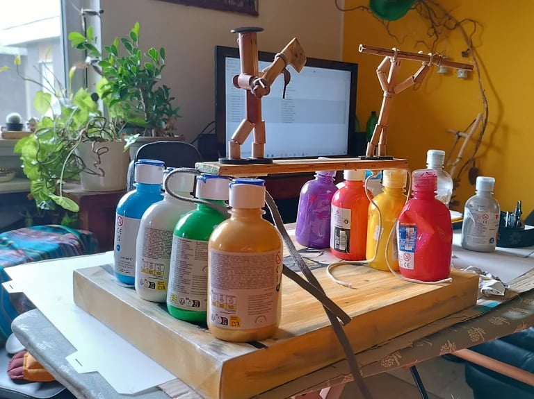 Laboratorio artigianale di quadri materici con flaconi di colore acrilico sul tavolo. - Guance Rosse