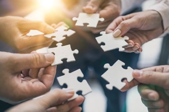 Mains tenant des pièces de puzzle, symbole d’un accompagnement complémentaire et global