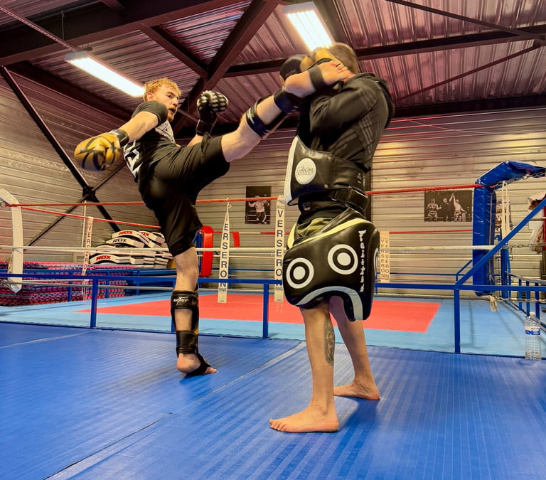 Entraînement de boxe : un boxeur en pleine frappe sur une patte d’ours tenue par son coach