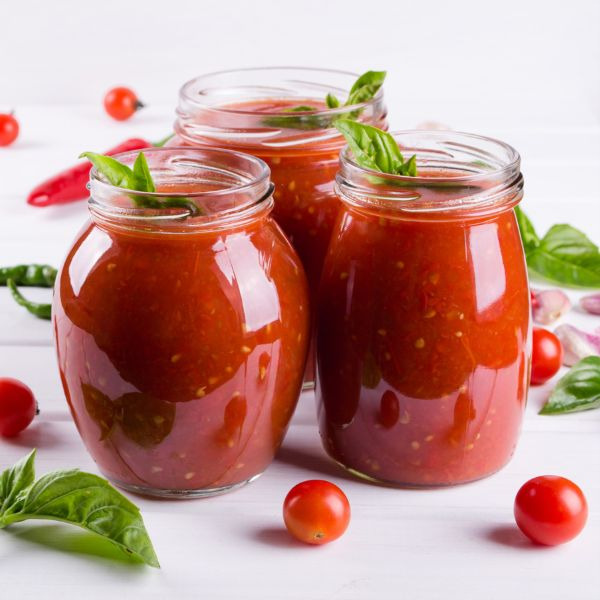 three jars of tomato sauce with basil and tomatoes