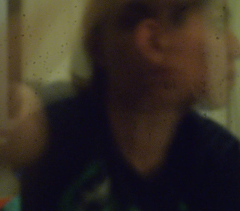 A blurry, low-light profile of a person viewed through a grainy, textured surface.