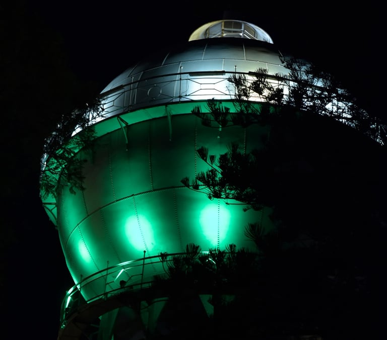 Illuminated industrial metal dome structure glowing with green lights at night.
