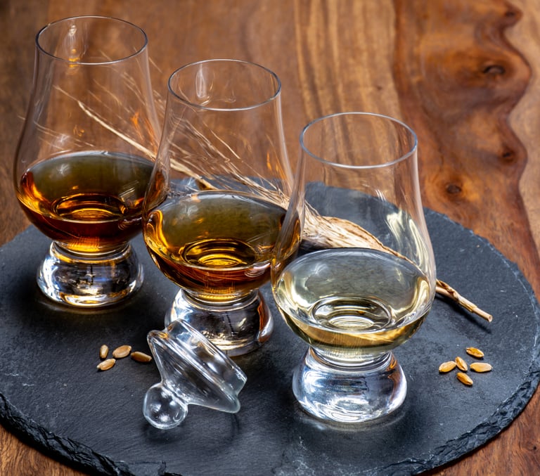a table with glasses of whisky on a black slate with barley grains