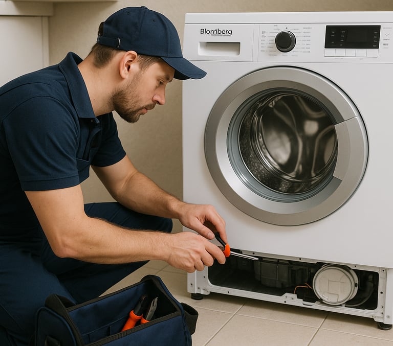 Blue Flame Works technician repairing a Blomberg front-load washer with tools on the floor.