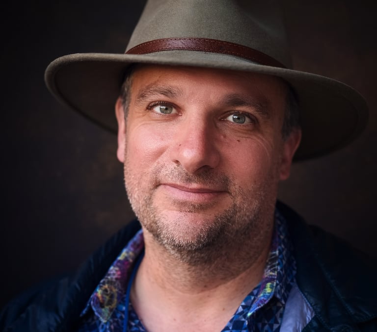 Headshot of middle-aged man wearing a hat.