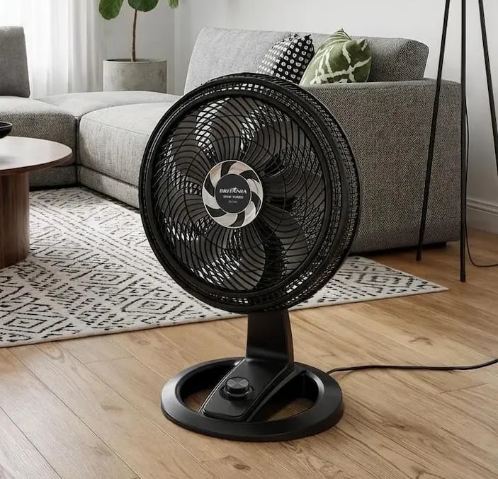 Black Britannia floor fan on wood floor in a modern living room interior.