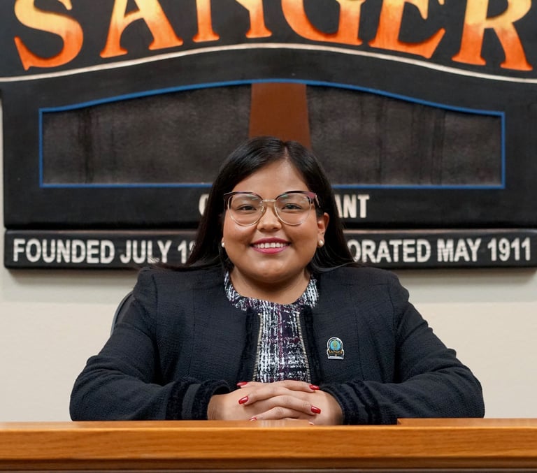 a woman in a black jacket and glasses sitting at a podium