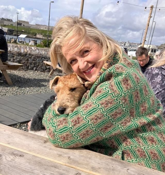 smiling blonde woman cuddling a dog