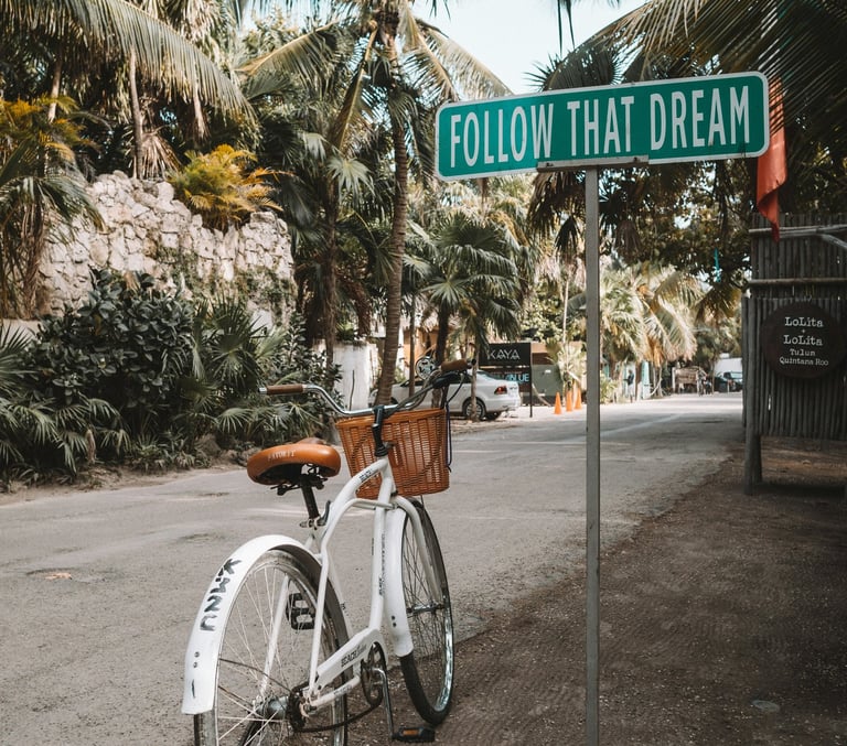 Vintage bicycle leaning against a pole with a 'Follow Your Dreams' sign