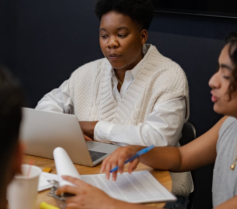 Young people sitting at a table, engaged in conversation about their work