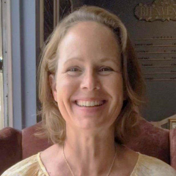 a woman in a yellow dress smiling and holding a cake