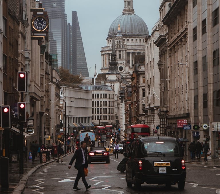A man crossing a London street. We also see a Black Cab, Red Bus, and the top of St Paul's Cathedral