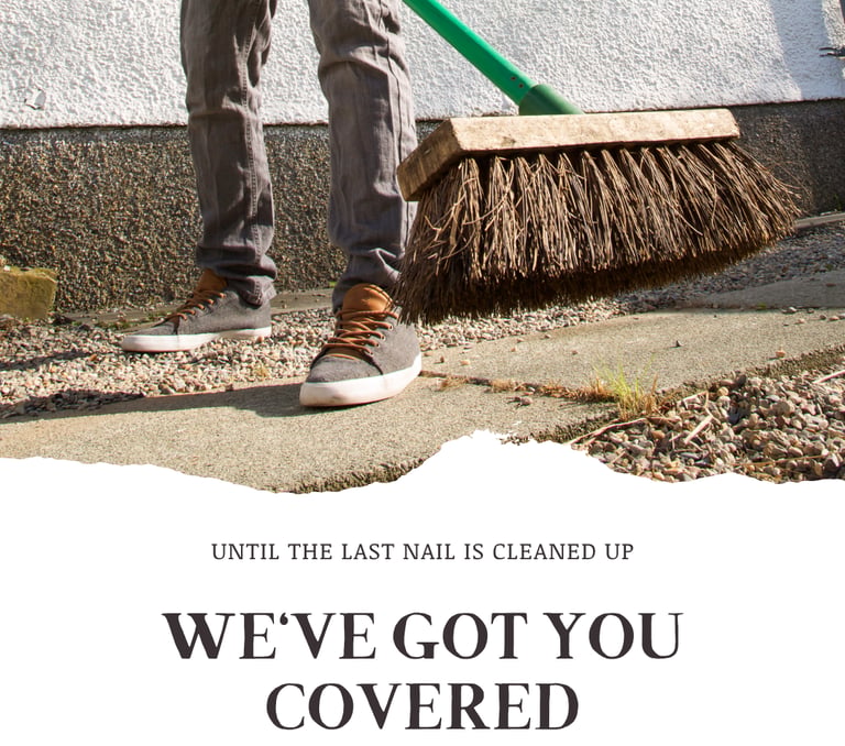 A worker sweeping up a job site at the end of a job in jeans and sneakers