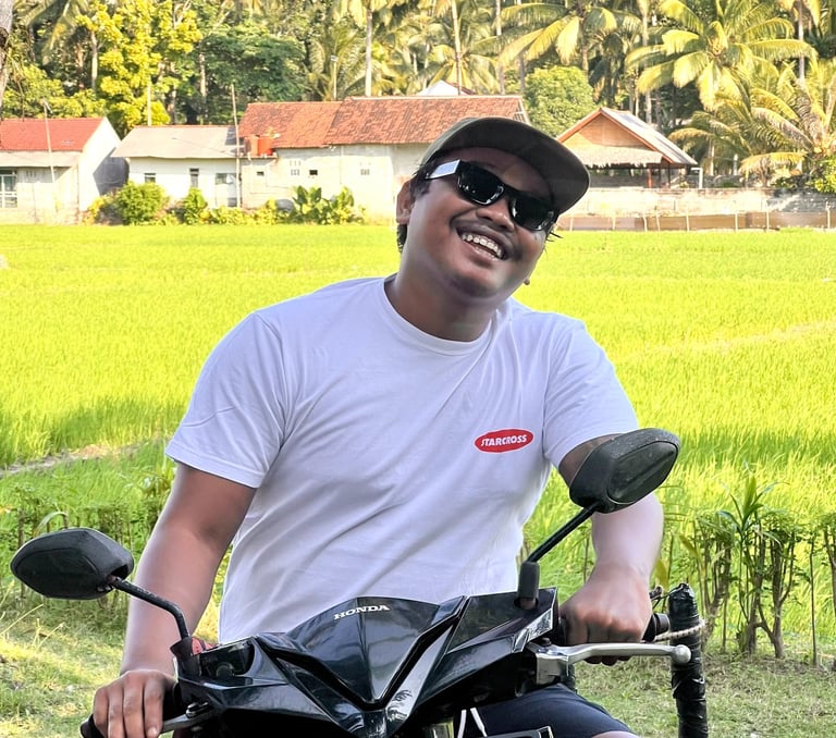 Ucup on motorbike with rice paddy in background