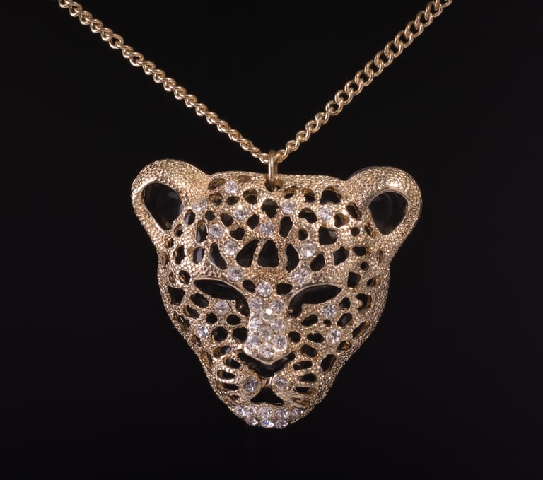 Picture of a Leopard's head shaped pendent on a dark background.