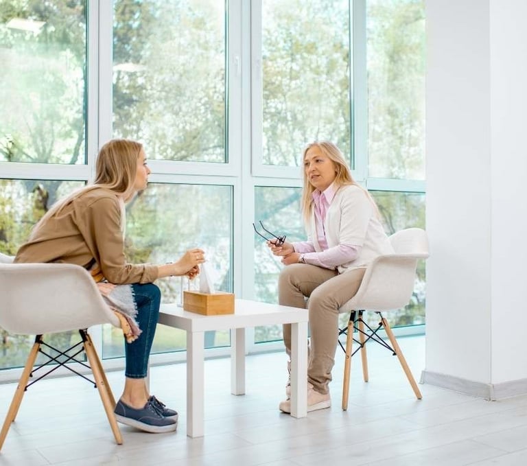 two women sitting at a table with a cup of coffee