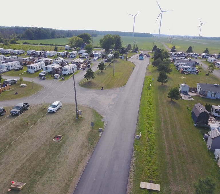 Aerial view of a spacious RV park and campground featuring paved roads and wind turbines.