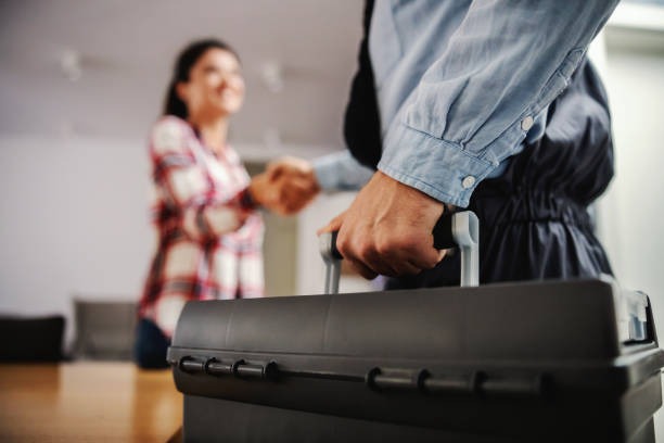 plumber making a deal with a prospect while holding a black tool box