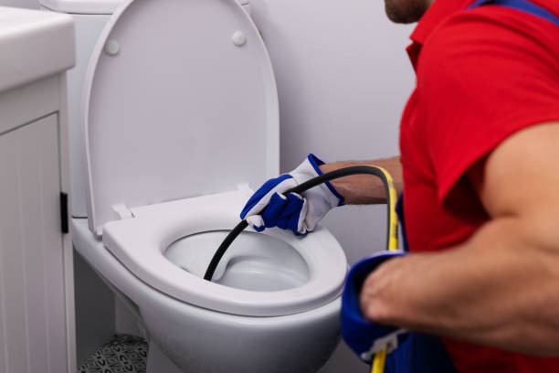plumber sucking water out of a toilet with a hose