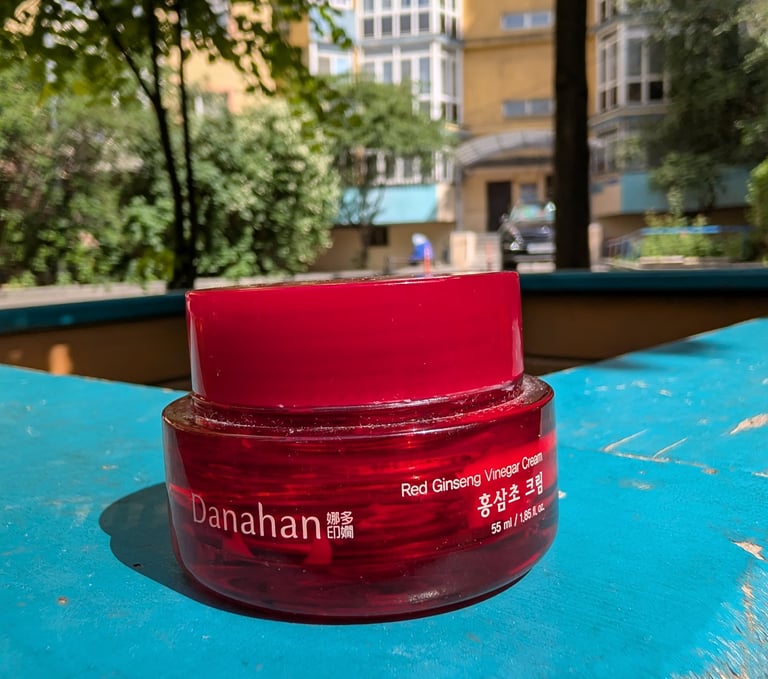 Danahan Red Ginseng Vinegar Cream in a red glass jar on a blue ledge with sunlight.