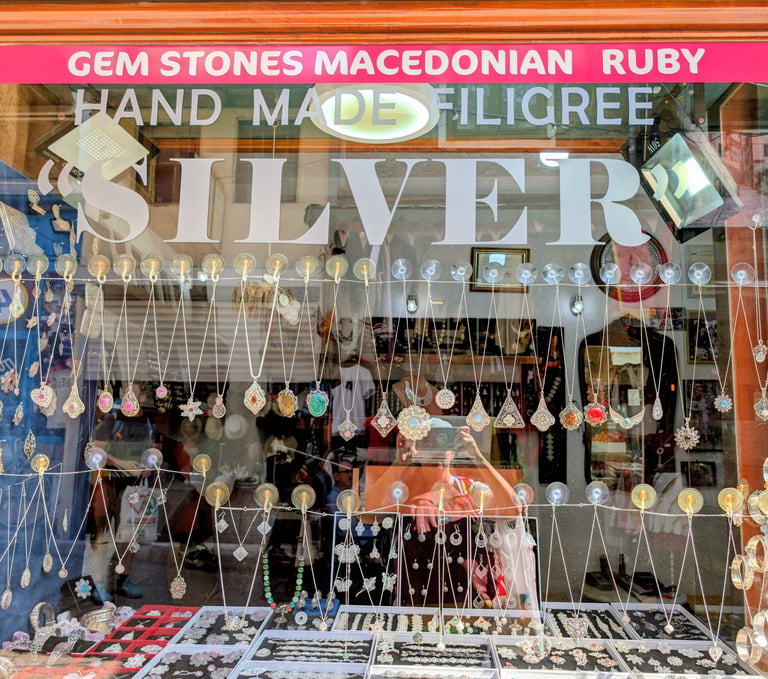 Handmade Macedonian ruby and silver filigree jewelry displayed in a shop window.