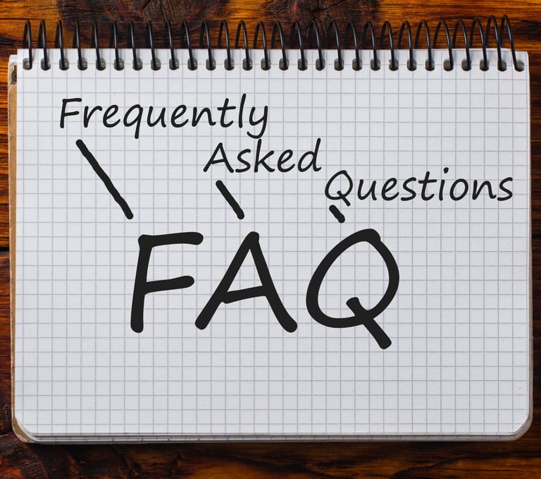 Handwritten FAQ acronym for Frequently Asked Questions on a spiral notebook with a wood background.