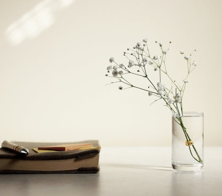 A vase, flowers and a book on a table 