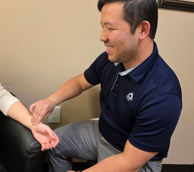 Dr. Xiong performing a pulse check on a patient's wrist in a clinic.