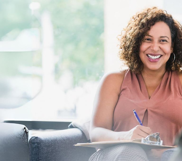 a woman sitting on a couch with a notebook and pen