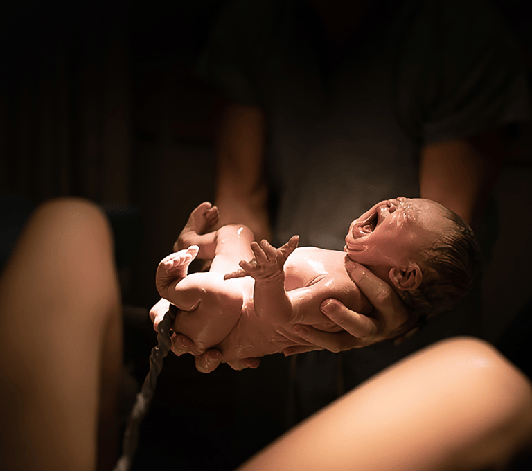 sage-femme pratiquant l'accouchement et bébé poussant son premier cri