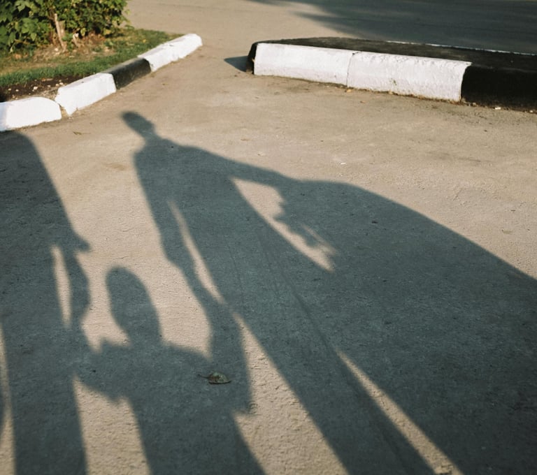 Schaduwen van mensen met een kind centraal, symboliseert perspectief en relationele verbinding.