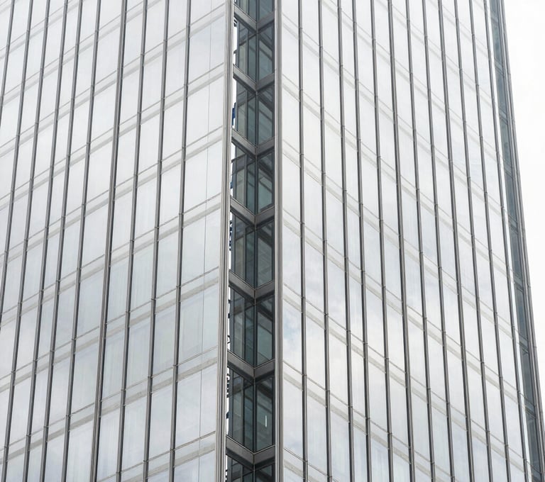 A vertical architectural photograph showing a detail of a glass and steel skyscraper in a South American / Brazilian city. The image is mostly pure white and light silver grey reflections with sharp charcoal grey geometric lines. High-end, premium mood.