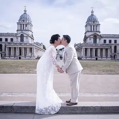 A wedding couple kissing in front of the Old Royal Naval College in Greenwich London.