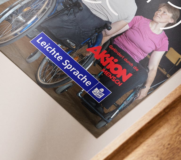 Auf einem Tisch liegt ein Flyer. Das Logo von AktionMensch und Leichte Sprache ist abgebildet.
