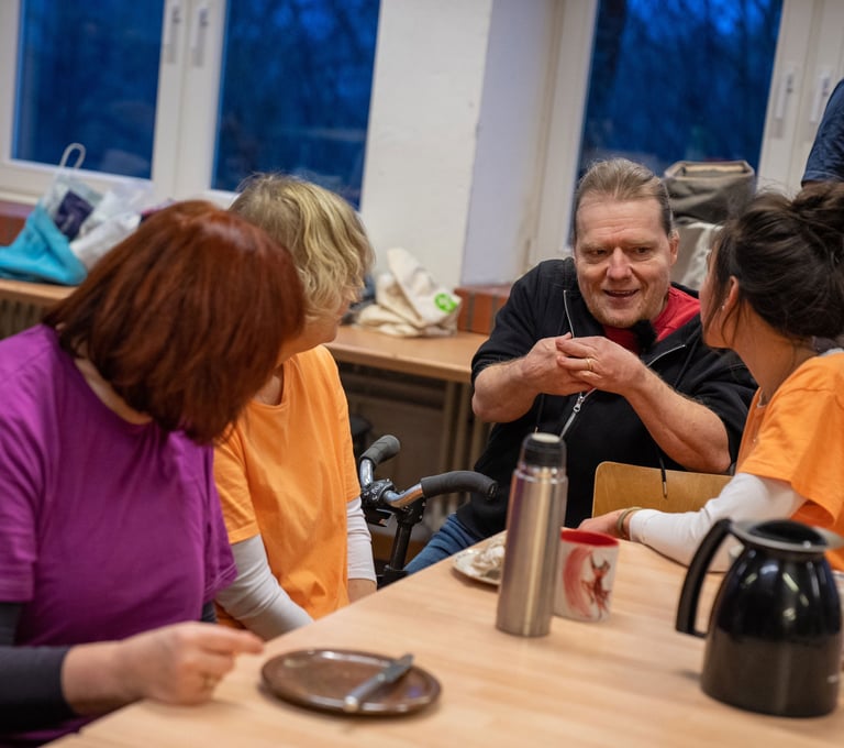 Eine Gruppe von Menschen mit und ohne Behinderungen unterhalten sich angeregt