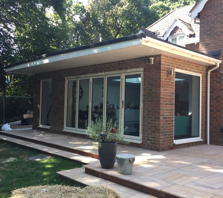 a bungalow house with bifold doors. there are 5 leaves on the doors and two white windows.