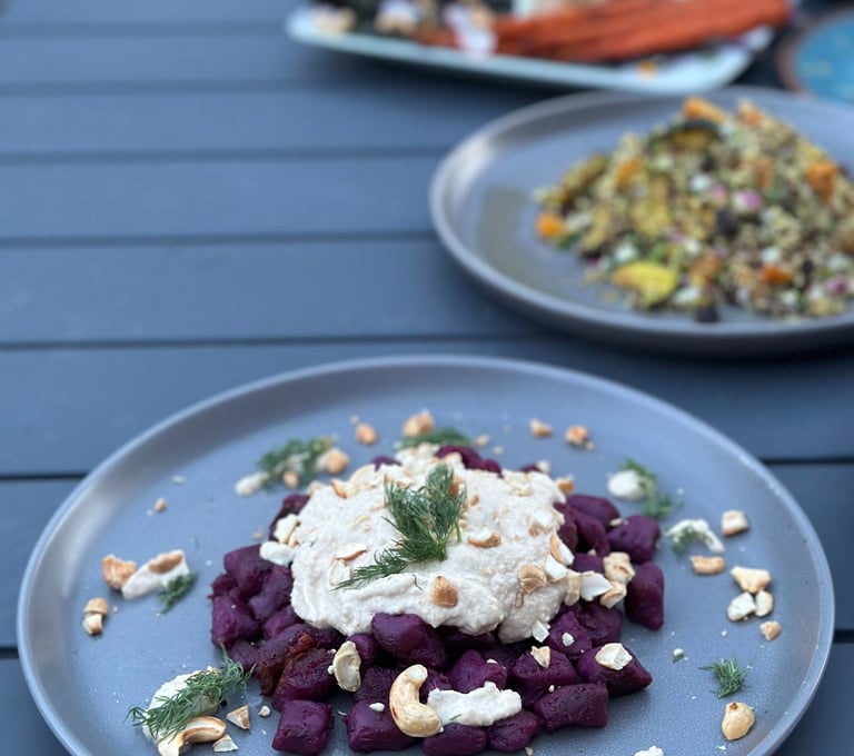 a plate of beetroot gnocchi on a table with a plate of food