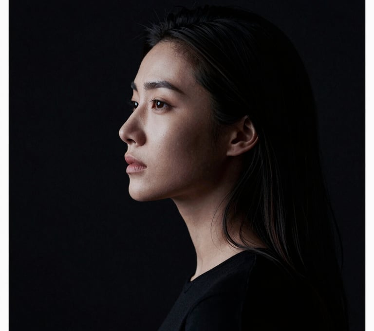 A high-contrast cinematic portrait of a woman, styled like a minimalist film poster. The composition uses negative space with midnight black tones and sharp soft white highlights on the profile.