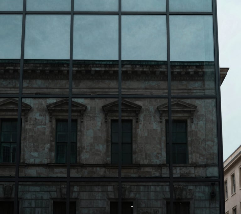 A minimalist portrait of a historic building facade reflected in a modern glass window. The contrast between old and new is captured in shades of Muted Teal and Dark Slate under a soft, overcast sky.