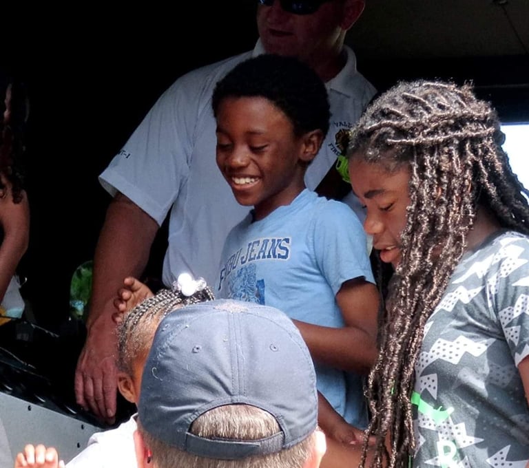 Boy smiling on firetruck at Reach Two event Brittany Woods