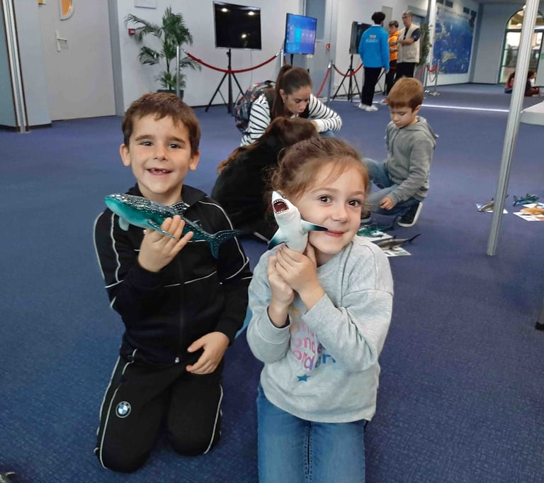 2 enfants avec des maquettes requins dans la main qui sourient