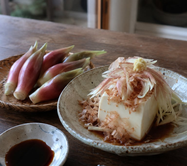 Hiyayakko Japanese cold tofu topped with katsuobushi and sliced myoga ginger on a ceramic plate.