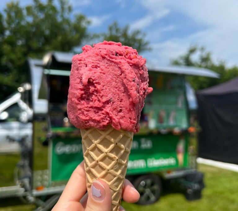 A vegan cone with one scoop of Summer Fruits sorbet ice cream. Georgio's event trailer behind